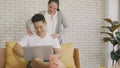 Family couple husband and wife laughing sitting on sofa using laptop computer working from home Royalty Free Stock Photo