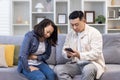 Family couple man and woman sitting on sofa at home asian family man trying to call doctor for sick wife Royalty Free Stock Photo