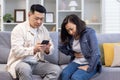 Family couple man and woman sitting on sofa at home asian family man trying to call doctor for sick wife Royalty Free Stock Photo