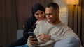 Family couple multiethnic interracial family African American man chatting on mobile phone muslim woman wife cuddle to Royalty Free Stock Photo