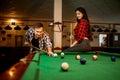 Couple plays in billiard room, male player aiming Royalty Free Stock Photo