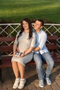 Family couple pregnant woman and a man sitting and hugging on bench in park and holds sneakers for newborn Royalty Free Stock Photo