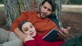 Family couple reading book at nature park spending weekend together close up. Royalty Free Stock Photo