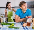 Family couple with serious faces quarrelling in kitchen