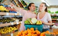 Family couple standing with full cart after shopping and pointing to shelves Royalty Free Stock Photo