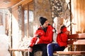 Family couple in a winter clothes sitting on a wooden bench Royalty Free Stock Photo