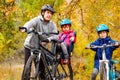 Family cycling in golden autumn park, active father and kids ride bikes, family sport and fitness