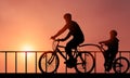 Family Cycling Together at Sunset time. Father and son silhouette Biking in front of beautiful sunset background