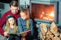 Family reading a book together near fireplace on Christmas eve Royalty Free Stock Photo