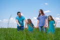 Family dad, mom and two children walking on green grass against blue sky. Happy caucasian parents with two daughters Royalty Free Stock Photo