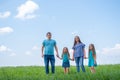 Family dad, mom and two children walking on green grass against blue sky. Happy caucasian parents with two daughters Royalty Free Stock Photo