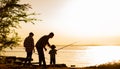 Family dad and two sons are fishing at sunset, silhouette of a man and two boys. Royalty Free Stock Photo