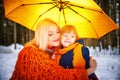 Family with daughter and mother in orange dress with yellow umbrella having fun and joy in woods, forest or park with Royalty Free Stock Photo