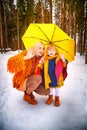 Family with daughter and mother in orange dress with yellow umbrella having fun and joy in woods, forest or park with Royalty Free Stock Photo