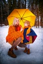 Family with daughter and mother in orange dress with yellow umbrella having fun and joy in woods, forest or park with Royalty Free Stock Photo