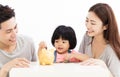 Family with daughter putting coins into piggy bank Royalty Free Stock Photo