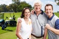 Family day on the green. Smiling golfing companions on the green with their golf cart in the background. Royalty Free Stock Photo