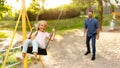 Family day. Happy girl swinging on swings having fun with father on playground, panorama, selective focus on schoolgirl