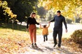 Family day. Happy smiling dad and mom having fun with their child daughter outdoors at autumn park. Couple lifting Royalty Free Stock Photo