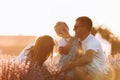 Family day. Happy young mom and dad tickle and hug their little daughter, enjoy relaxing in lavender field at sunset Royalty Free Stock Photo