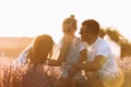 Family day. Happy young mom and dad tickle and hug their little daughter, enjoy relaxing in lavender field at sunset Royalty Free Stock Photo