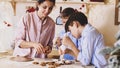 Family is decorating a Christmas cookies with pastry bag at home kitchen.