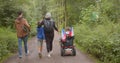 Family disabled person moves through forest park take steps carriage rolls