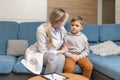 A family doctor examines a little boy at home. Pediatrician girl treats a child