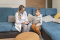 A family doctor examines a little boy at home. Pediatrician girl treats a child