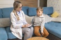 A family doctor examines a little boy at home. Pediatrician girl treats a child