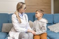 A family doctor examines a little boy at home. Pediatrician girl treats a child