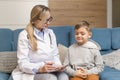 A family doctor examines a little boy at home. Pediatrician girl treats a child