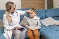 A family doctor examines a little boy at home. Pediatrician girl treats a child