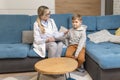 A family doctor examines a little boy at home. Pediatrician girl treats a child