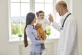 Family doctor.Senior doctor giving high five to girl at medical office. Little patient with her mommy on visit to Royalty Free Stock Photo