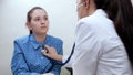 Family doctor therapist listens to heart and lungs with stethoscope of girl patient in office. Young woman at doctor& x27;s