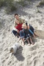 Family With Dog Relaxing On Sandy Beach Royalty Free Stock Photo