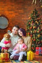 Family with dog sits on the floor near the festive Christmas tree Royalty Free Stock Photo