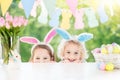 Kids with bunny ears and eggs on Easter egg hunt. Royalty Free Stock Photo