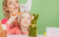 Family Easter. Mother and daughter with painting eggs. Cute little child girl is wearing bunny ears.