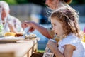 Family eating at barbecue party dinner in garden, little girl drinking water and enjoying it. Royalty Free Stock Photo