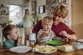 Family eating breakfast together in home kitchen. Healthy breakfast or snack before kindergarden, school and work. Royalty Free Stock Photo