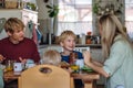 Family eating breakfast together in home kitchen. Healthy breakfast or snack before kindergarden, school and work. Royalty Free Stock Photo