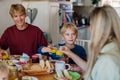 Family eating breakfast together in home kitchen, toasting with juice. Healthy breakfast or snack before school and work Royalty Free Stock Photo