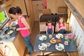 Family eating together in RV interior, mother and kids travel in motorhome camper, caravan on family vacation with children