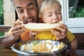 Family eating fresh sweet melon on terrace. Father and his toddler son biting together slice of honeymelon fruit. Summer food Royalty Free Stock Photo