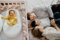 a family with an eldest son lies at the crib with a newborn baby.
