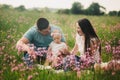 Family enjoying life together in the summer field with wild flowers. Happy young family outdoors. Mother, father are hugging their Royalty Free Stock Photo