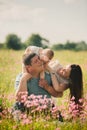 Family enjoying life together in the summer field with wild flowers. Happy young family outdoors. Mother, father are hugging their Royalty Free Stock Photo