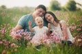 Family enjoying life together in the summer field with wild flowers. Happy young family outdoors. Mother, father are hugging their Royalty Free Stock Photo